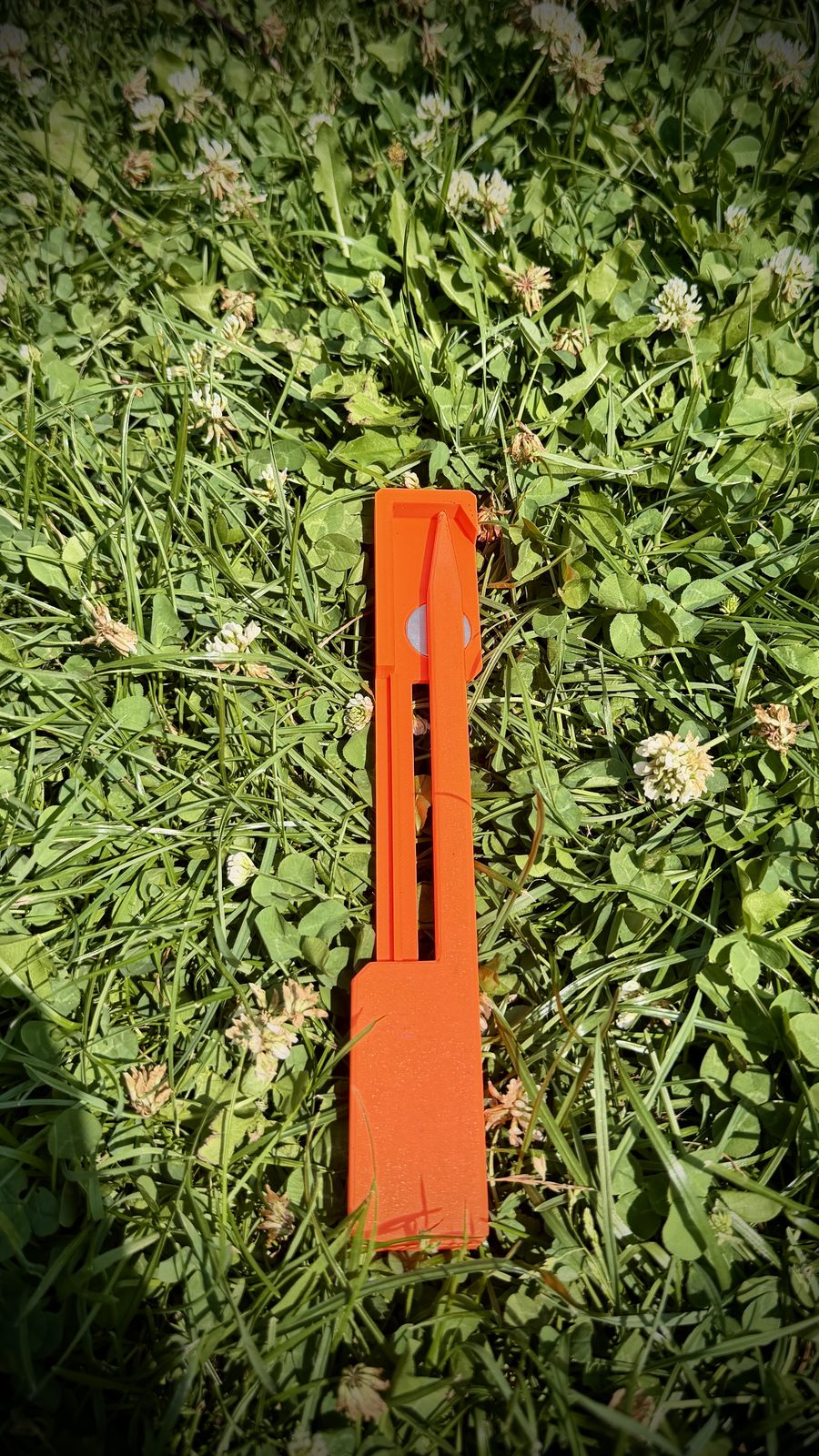 Detail markeru nástřelu z 3D tisku — oranžové tělo, kapsa na magnet, hrot do země