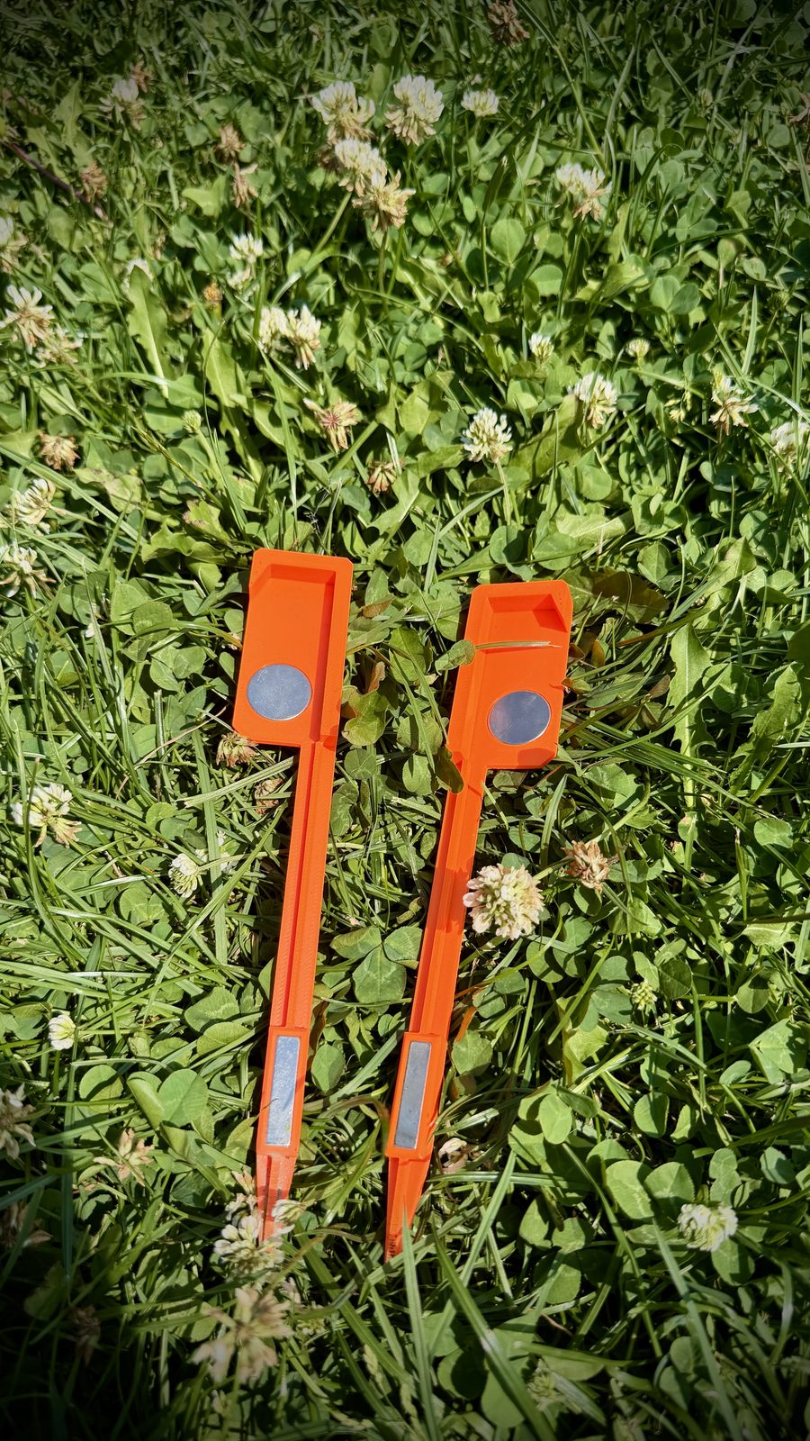 Dva markery nástřelu s magnety a špičatým hrotem položené v trávě