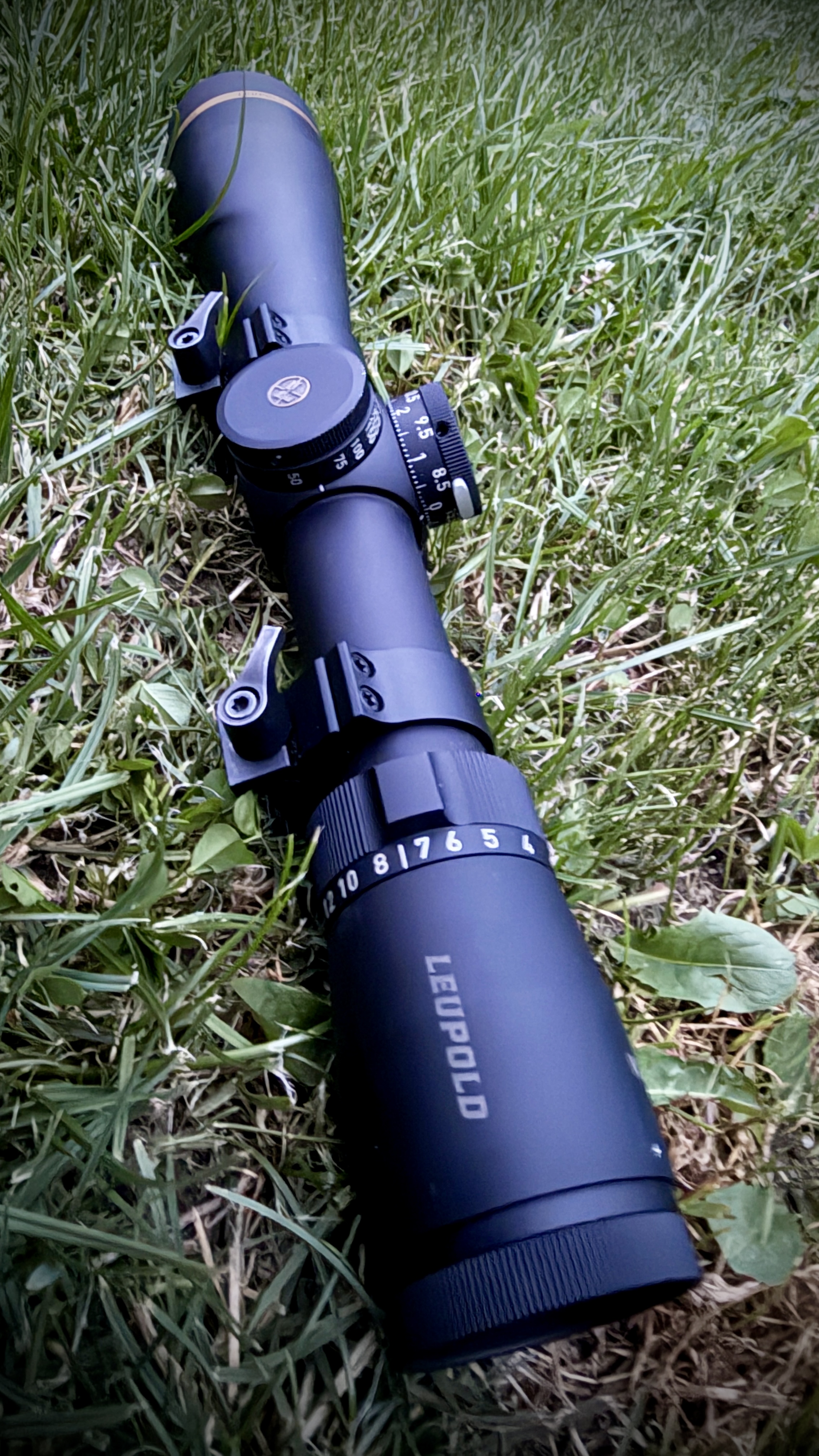 Kolba puškohledu Leupold s ryskami vzdálenosti a nastavením zvětšení v trávě